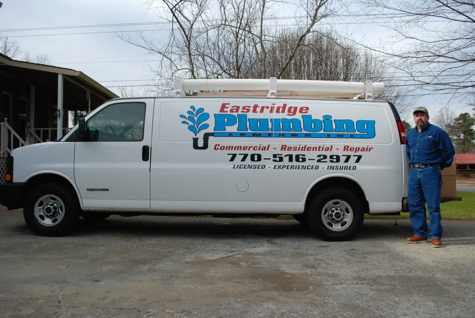 Johnny Eastridge beside the Eastridge Plumbing van, lettered with the company logo, 770-516-2977, and Licensed - Experienced - Insured