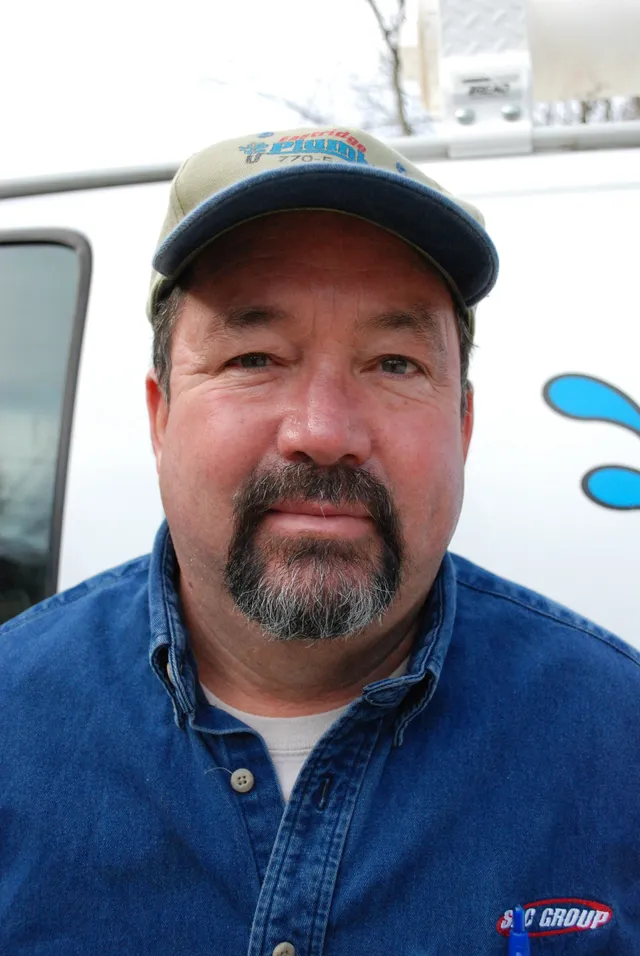 Johnny Eastridge, owner and Master Plumber, in his Eastridge Plumbing cap in front of the company van