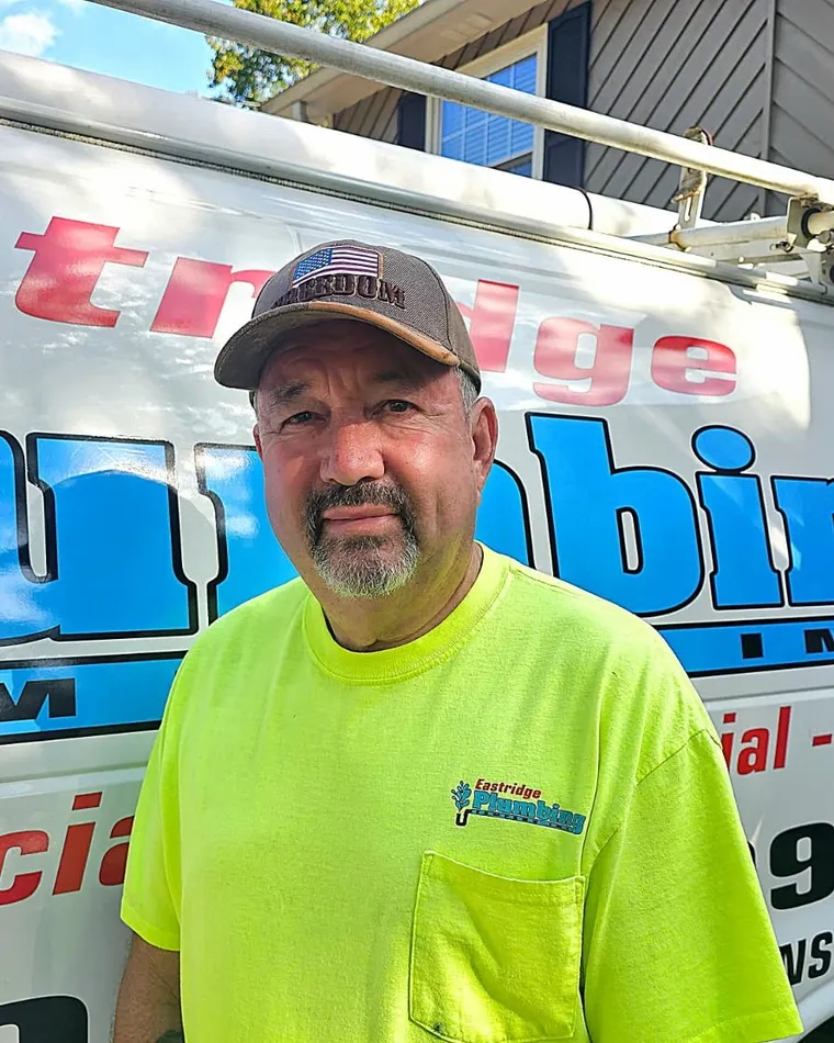 Johnny Eastridge, owner and Master Plumber, in an Eastridge Plumbing shirt in front of the company van