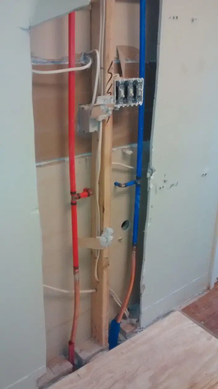 Hot and cold supply lines roughed in through open wall framing during a remodel