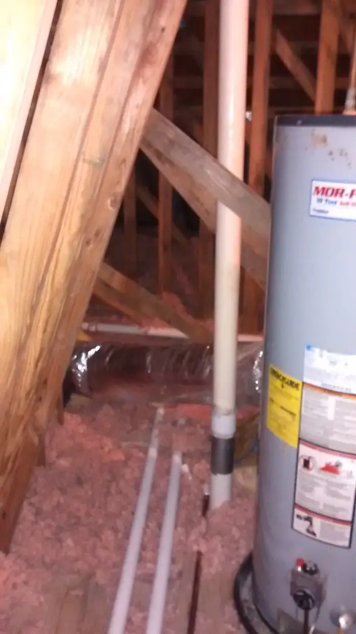 A tank water heater installed in an attic space, with new supply piping run to it